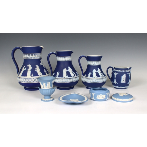 7 - Four Jasperware Wedgwood jugs with Royal blue ground, early 20th century, each decorated with classi... 