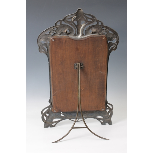 134 - An Art Nouveau pewter easel-backed mirrorcast with a reclining female, leaf and berries amongst sinu... 