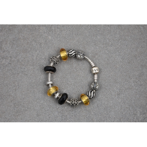 573 - A Pandora bracelet with eleven silver charmsin silver, black and amber tones, most set with crystals... 