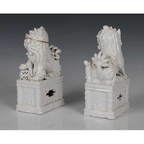 804 - A pair of Chinese blanc de chine porcelain Foo Dogswith incense stick holders, on plinths, 20.5cm. h... 