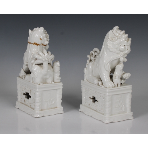 804 - A pair of Chinese blanc de chine porcelain Foo Dogswith incense stick holders, on plinths, 20.5cm. h... 