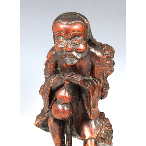 831 - A carved wooden Oriental root figure of an old man with a gourd leaning on a stick33cm. high.