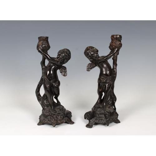 1100 - A pair of French, late 19th century, patinated bronze candlesticks in the form of cherubsholding up ... 