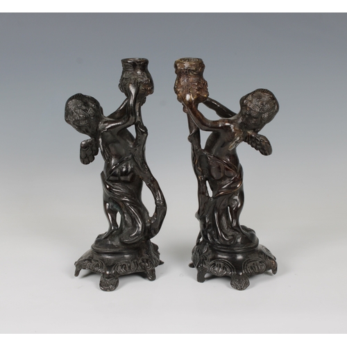 1100 - A pair of French, late 19th century, patinated bronze candlesticks in the form of cherubsholding up ... 