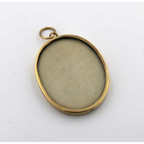 1136 - An 18ct yellow gold (tested) open glass locket incorporating a floral miniature3.6cm.