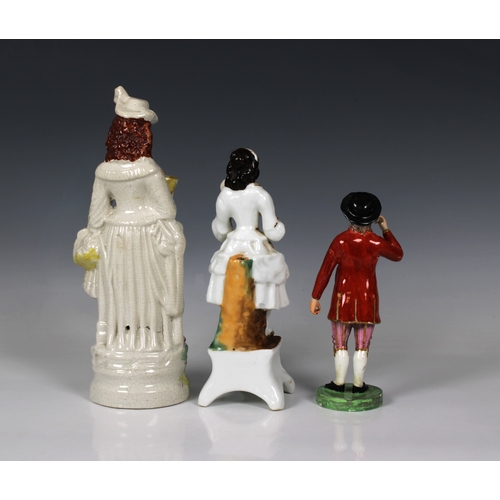 2063 - Three 19th century Staffordshire ceramic figures, of an elegantly dressed young woman 26.5cm. high, ... 