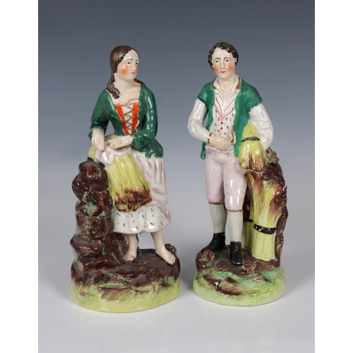 2075 - A pair of 19th century Staffordshire ceramic figures of a young country couple, each wearing a green... 