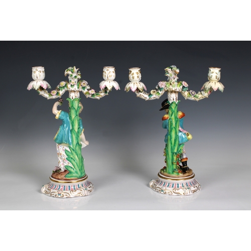 2085 - A pair of Continental porcelain twin branched candelabra, featuring a boy and girl, applied flowers,... 