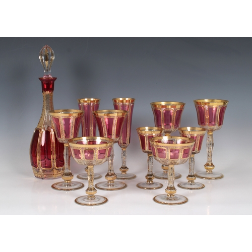 2131A - A Bohemian gilt cranberry decanter and glasses, each having raised panels with gilt trim and all ove... 