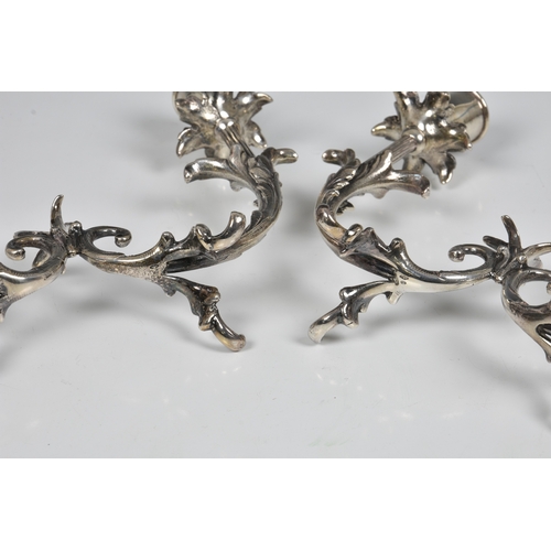 122 - A pair of Italian silver twin branch table candelabra stamped 800 and lozenge mark, having flower he... 