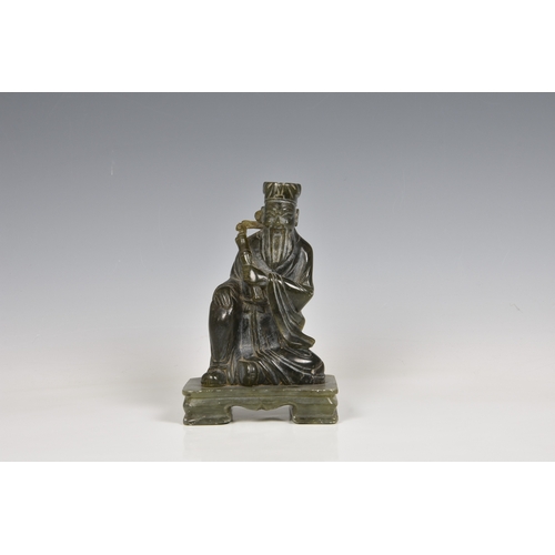 146 - An Oriental green hardstone figure of a deity / scholar sitting upon a raised platform, 7 3/8in. (18... 