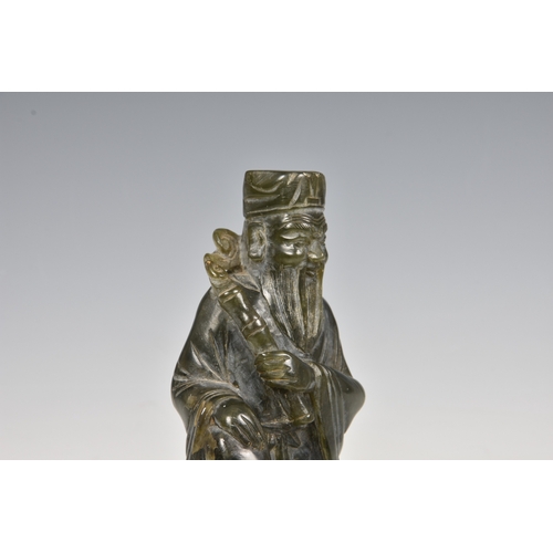 146 - An Oriental green hardstone figure of a deity / scholar sitting upon a raised platform, 7 3/8in. (18... 