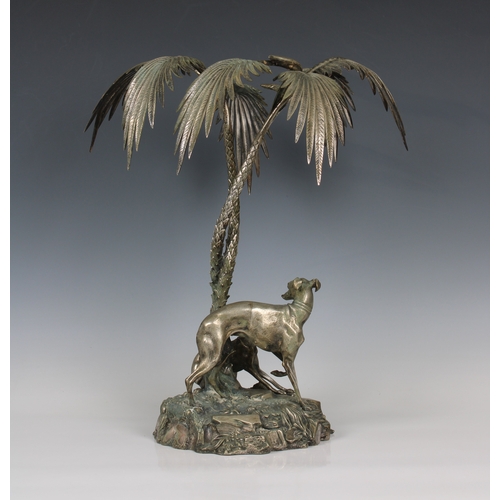 196 - A silver plated centrepiece in the form of two greyhounds sheltering beneath palm trees in the manne... 