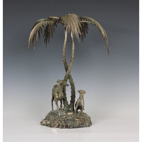 196 - A silver plated centrepiece in the form of two greyhounds sheltering beneath palm trees in the manne... 