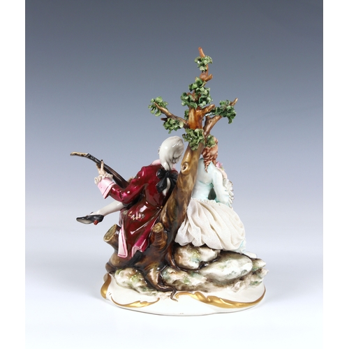 265 - A Capodimonte figure of a courting couple in 18th century costume, seated beneath a tree, the gentle... 