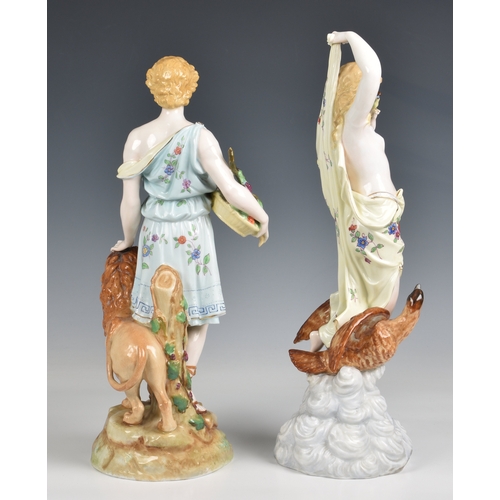 284 - A pair of Rudolstadt porcelain figures in floral dress of Heracles standing with a lion and Hebe kne... 