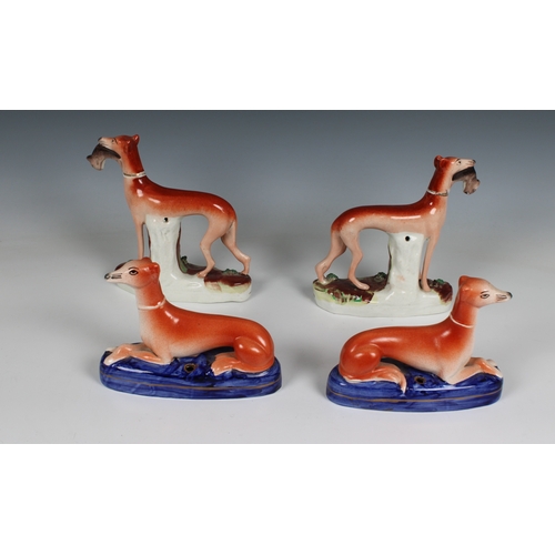 320 - Two pairs of Staffordshire pottery greyhounds two with rabbits in their mouths, 5½in. (14cm.) high &... 