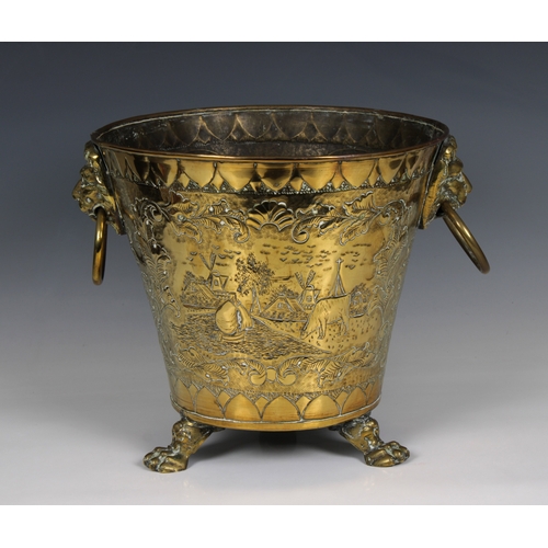 632 - A Brass embossed and etched Coal Bucket with Lion Ring Handles raised on three loin paw feet, decora... 