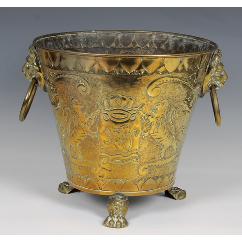 632 - A Brass embossed and etched Coal Bucket with Lion Ring Handles raised on three loin paw feet, decora... 