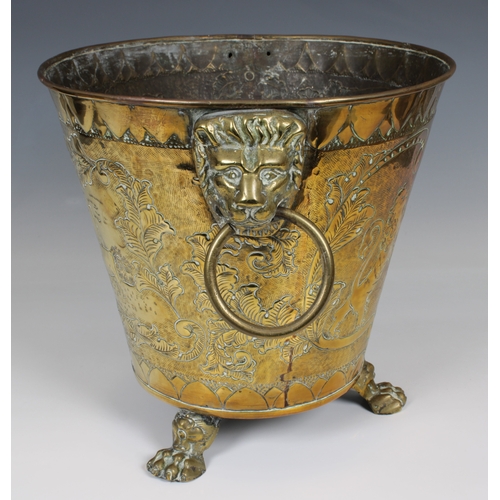 632 - A Brass embossed and etched Coal Bucket with Lion Ring Handles raised on three loin paw feet, decora... 