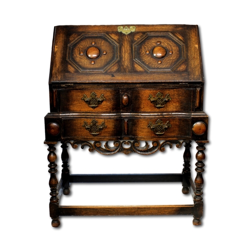 643 - A dark oak Jacobean style bureau on stand the sloping top with carved roundels within octagonal frie... 