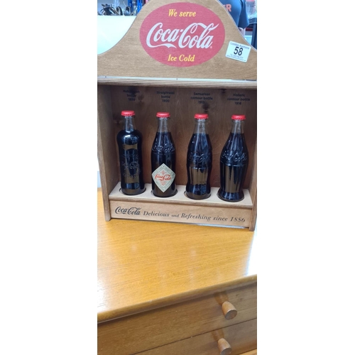 58 - Set of 4 Historic Coca Cola Bottles in a Wooden Display Cabinet. released c.2012