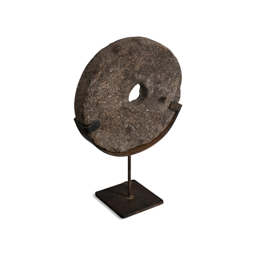 15 - A FLAT CIRCULAR LIMESTONE QUERN STONE,  with pierced centre on steel stand. 68cm high, 45cm wide, 9c... 