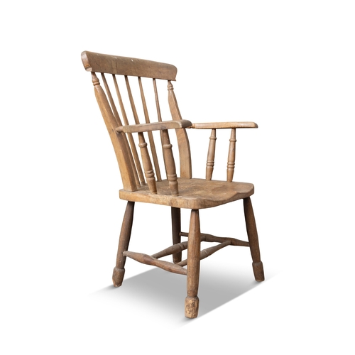 150 - A PINE CURVED RAILBACK ARMCHAIR  the stick back, flat armrests and dished saddle seat on splayed tur... 