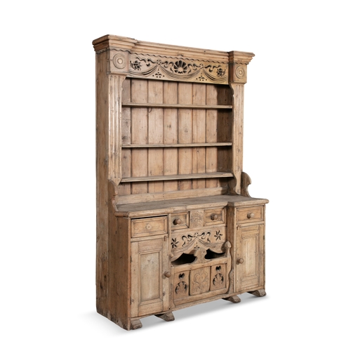 171 - AN IRISH STRIPPED PINE KITCHEN DRESSER,  the carved and pierced frieze above open shelves on a base ... 