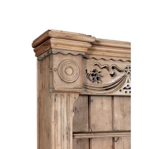 171 - AN IRISH STRIPPED PINE KITCHEN DRESSER,  the carved and pierced frieze above open shelves on a base ... 