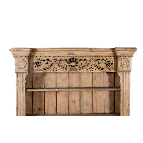 171 - AN IRISH STRIPPED PINE KITCHEN DRESSER,  the carved and pierced frieze above open shelves on a base ... 