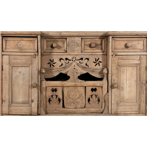 171 - AN IRISH STRIPPED PINE KITCHEN DRESSER,  the carved and pierced frieze above open shelves on a base ... 