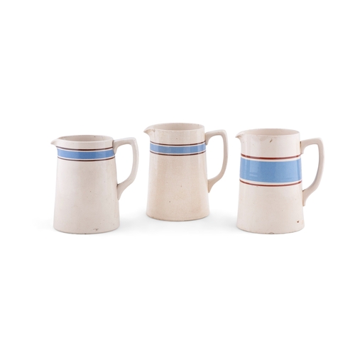 214 - A SET OF THREE CARRIGALINE POTTERY JUGS  in various sizes, with a large mug, plain cream with blue b... 