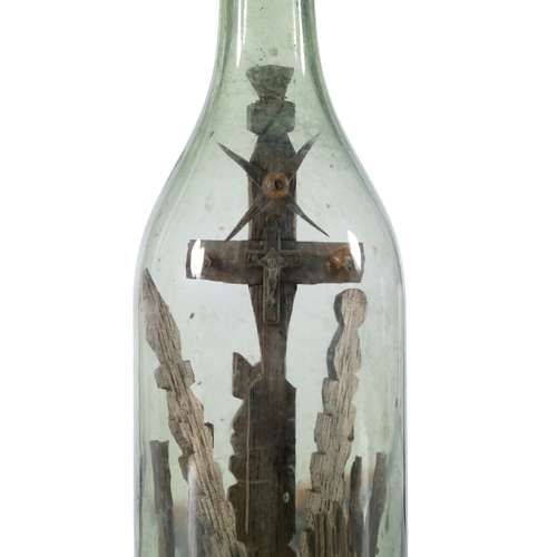 251 - AN UNUSUAL IRISH FOLK ART 'GOD IN A BOTTLE'  the green tinged glass bottle with crucifix mounted int... 