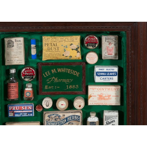 261 - A COLLECTION OF VICTORIAN CHEMIST SHOP PRODUCTS,   in a stained wood wall display case, 67cm, 56.7cm... 