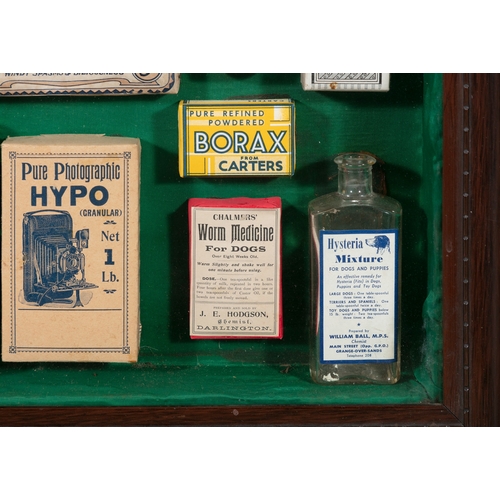 261 - A COLLECTION OF VICTORIAN CHEMIST SHOP PRODUCTS,   in a stained wood wall display case, 67cm, 56.7cm... 