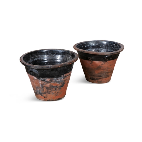 70 - A PAIR OF TERRACOTTA MILK CROCKS,  the moulded rim above black glazed body with thrown handles. 32cm... 