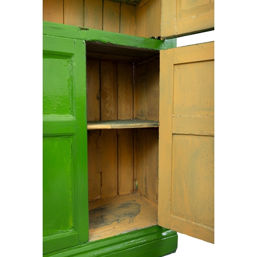 83 - A 19TH CENTURY GREEN PAINTED CUBOARD  the dentil cornice over twin four panel enclosing fitted inter... 