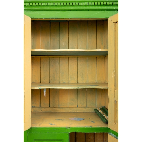 83 - A 19TH CENTURY GREEN PAINTED CUBOARD  the dentil cornice over twin four panel enclosing fitted inter... 