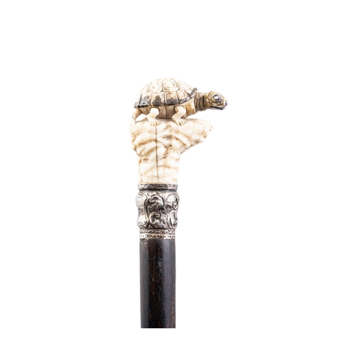 28 - *A WALKING CANE,   with a carved bone handle in the of a turtle perched on a rock above a white meta... 