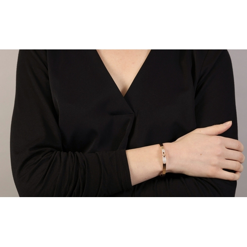 122 - AN 18K GOLD AND DIAMOND 'KELLY BRACELET' BY HERMÈS  The polished oval gold bangle with 'Kelly' turn-... 