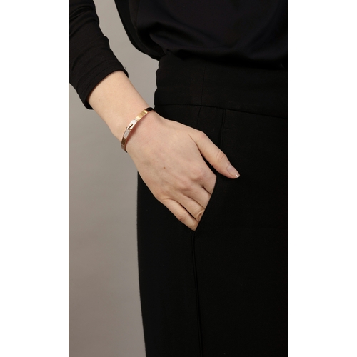 122 - AN 18K GOLD AND DIAMOND 'KELLY BRACELET' BY HERMÈS  The polished oval gold bangle with 'Kelly' turn-... 