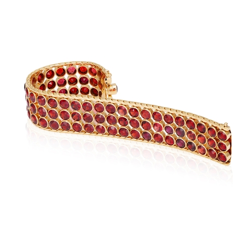 38 - A GARNET AND GOLD BRACELET, CIRCA 1950  The wide band collet-set with circular-cut garnets, to fine-... 