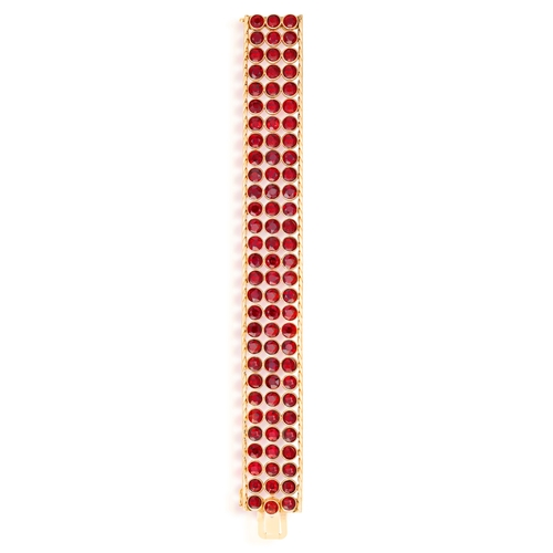 38 - A GARNET AND GOLD BRACELET, CIRCA 1950  The wide band collet-set with circular-cut garnets, to fine-... 