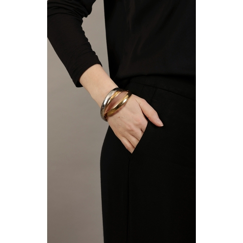 7 - A GOLD 'TRINITY' BANGLE, BY CARTIER  Composed of three interlocking polished 18K tri-coloured gold b... 