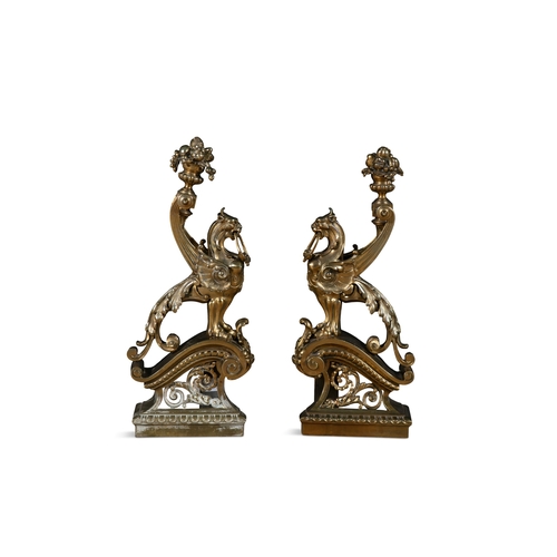 41 - A PAIR OF BRASS FIRE DOGS,   in the form of winged griffins, perched on pierced brackets. 53cm high