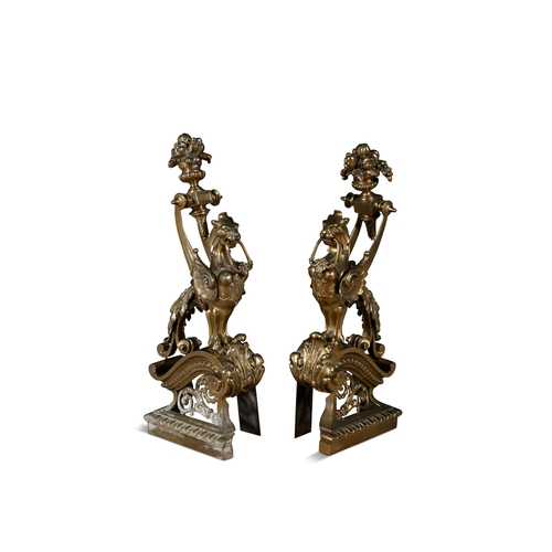 41 - A PAIR OF BRASS FIRE DOGS,   in the form of winged griffins, perched on pierced brackets. 53cm high