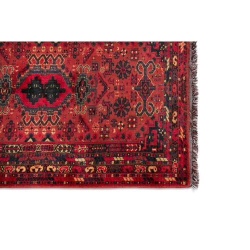 51 - A TURKISH WOOL RUNNER WITH RED GROUND, 300CM X 95CM  the central field woven with three geometric me... 