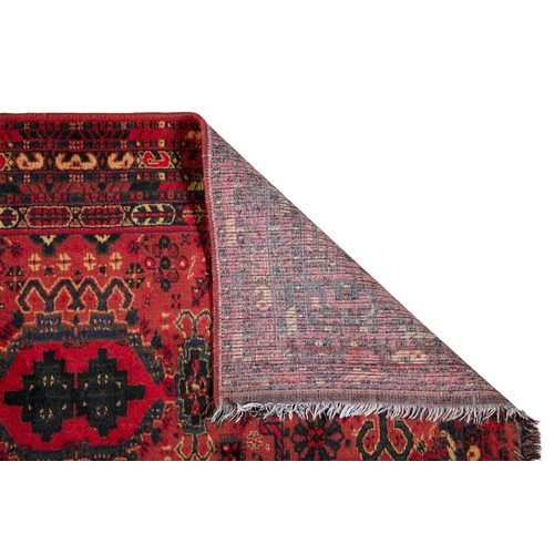 51 - A TURKISH WOOL RUNNER WITH RED GROUND, 300CM X 95CM  the central field woven with three geometric me... 