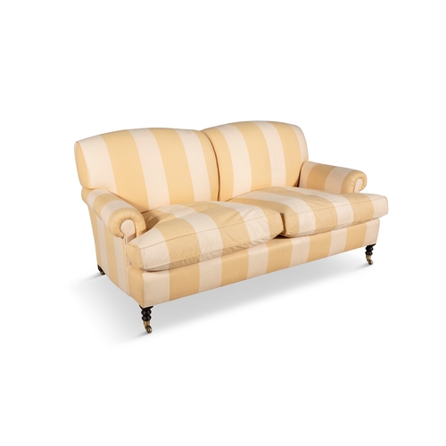 22 - AN UPHOLSTERED HOWARD STYLE SOFA  covered in a yellow and beige striped fabric, with loose seat cush... 